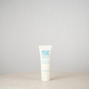 Tube of 'Keep My Curl Defining Cream' by Eleven on a light gray background