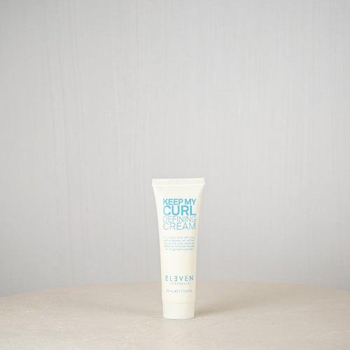 Tube of 'Keep My Curl Defining Cream' by Eleven on a light gray background