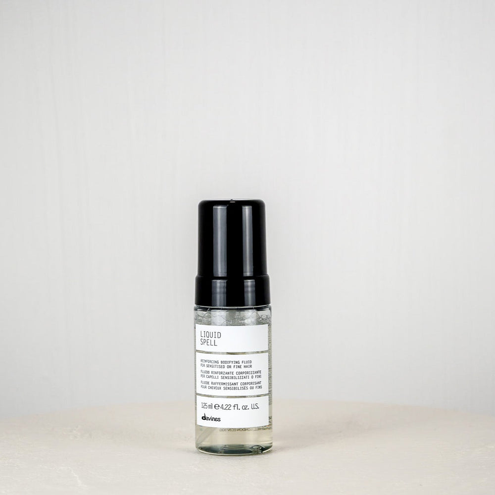 Skincare serum bottle with black cap on a white surface against a light gray background