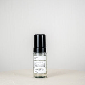 Skincare serum bottle with black cap on a white surface against a light gray background