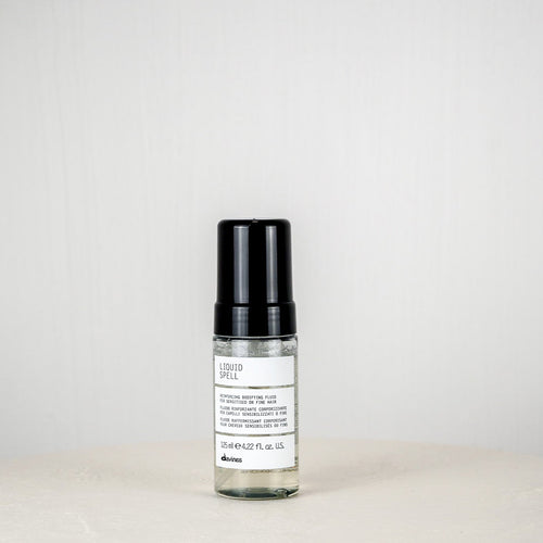 Skincare serum bottle with black cap on a white surface against a light gray background