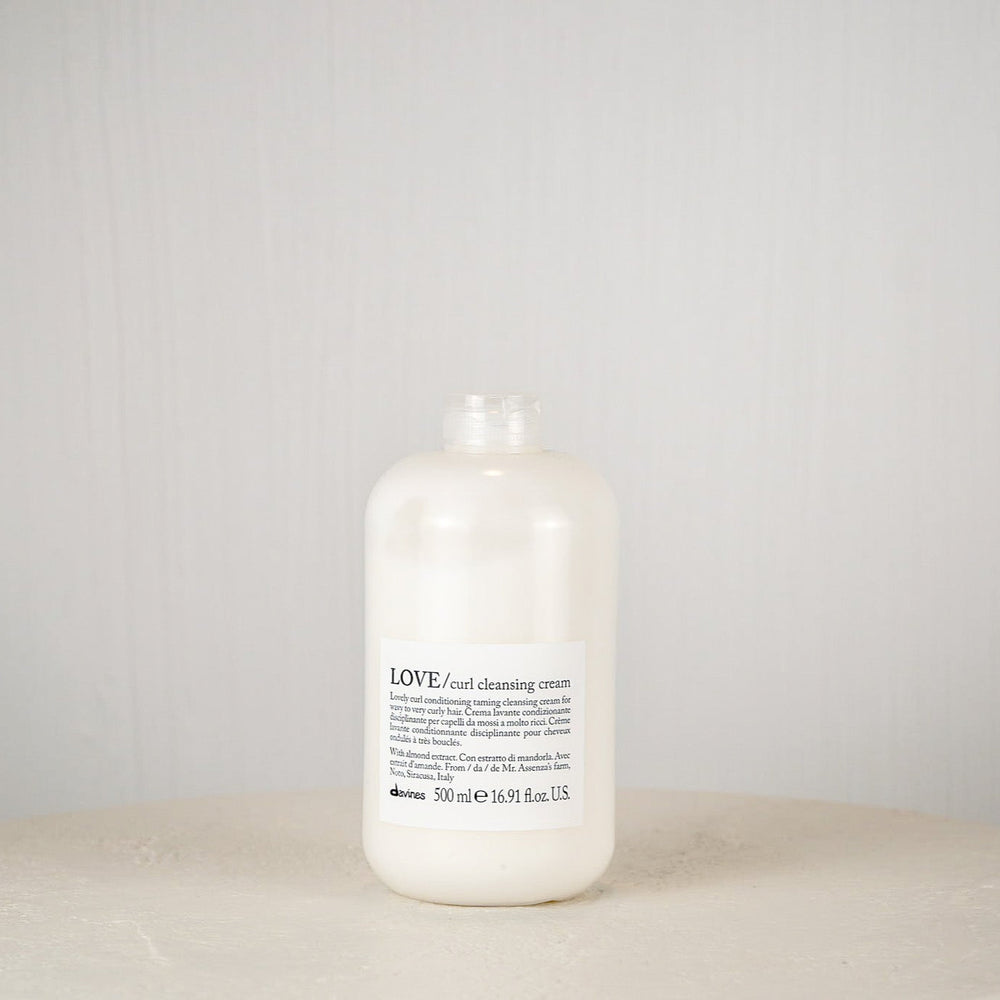 White bottle labeled 'LOVE' on a round white surface with a light gray background