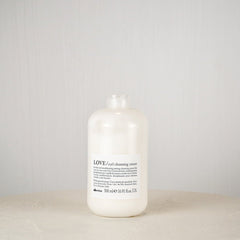 White bottle labeled 'LOVE' on a round white surface with a light gray background