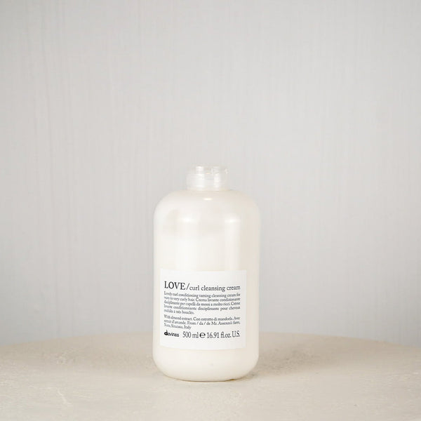 White bottle labeled 'LOVE' on a round white surface with a light gray background