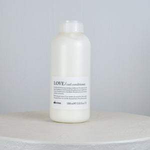 Bottle of Davines LOVE/curl conditioner on a light gray background