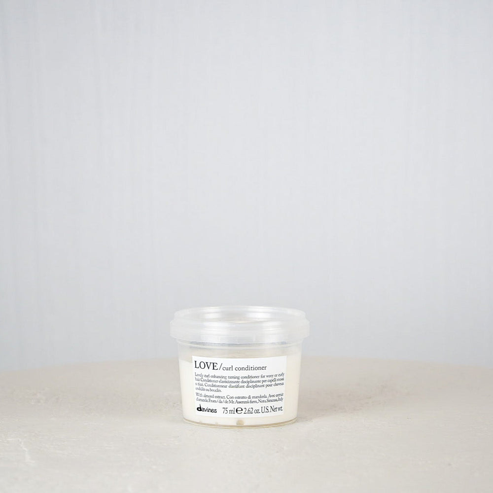 White candle with a label on a white surface against a gray background