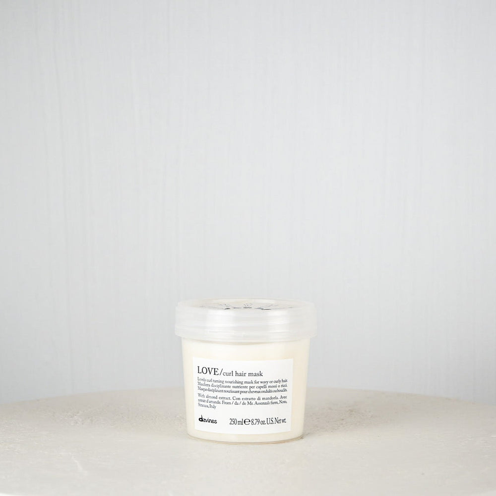 Bottle of Davines LOVE Curl hair mask on a white surface with a gray background