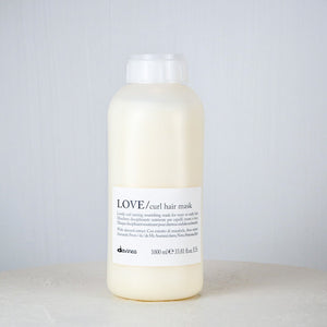 Bottle of Davines LOVE Curl hair mask on a white surface with a gray background