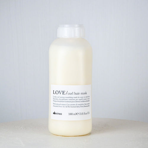 Bottle of Davines LOVE Curl hair mask on a white surface with a gray background