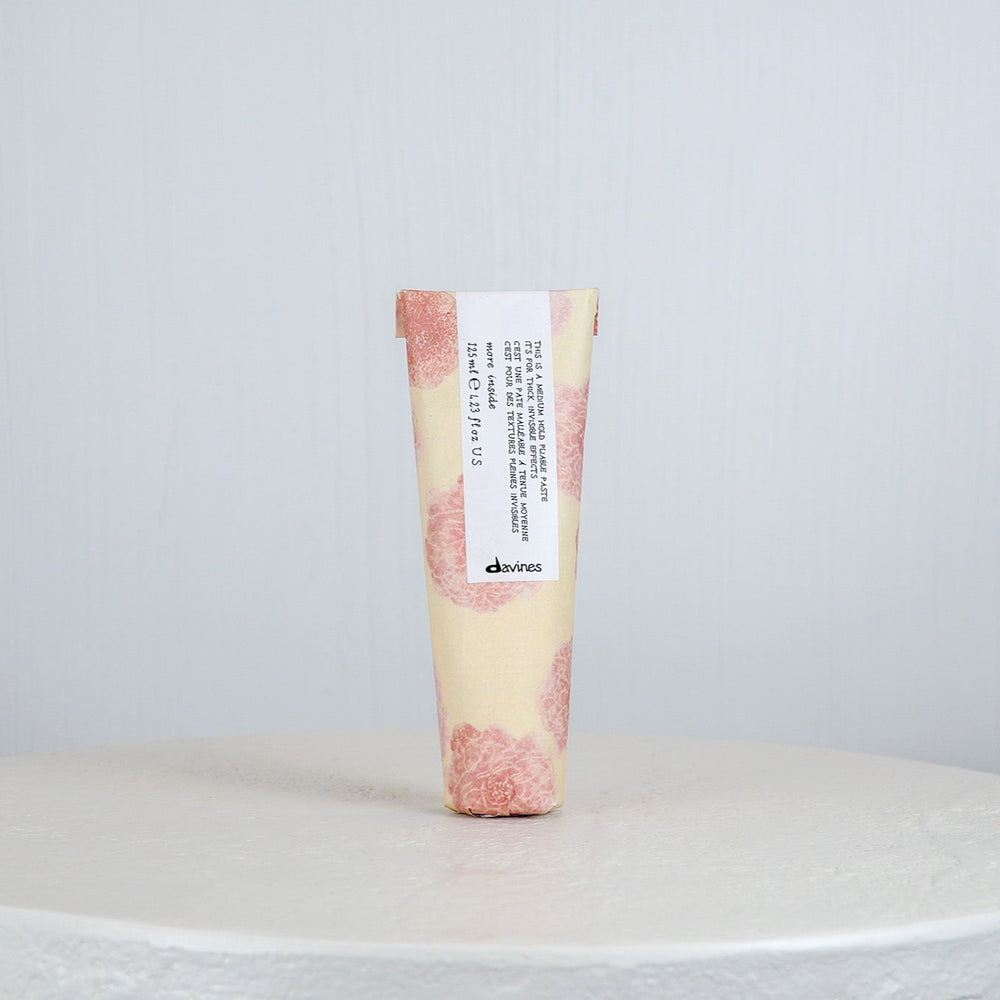Tube of Davines hair product on a white surface with a light gray background