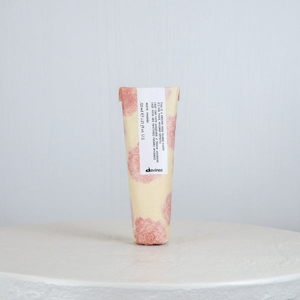 Tube of Davines hair product on a white surface with a light gray background