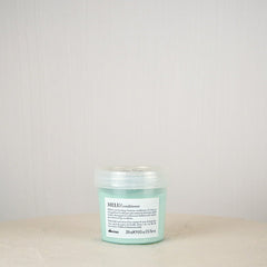 Green jar with label on a white surface against a light gray background