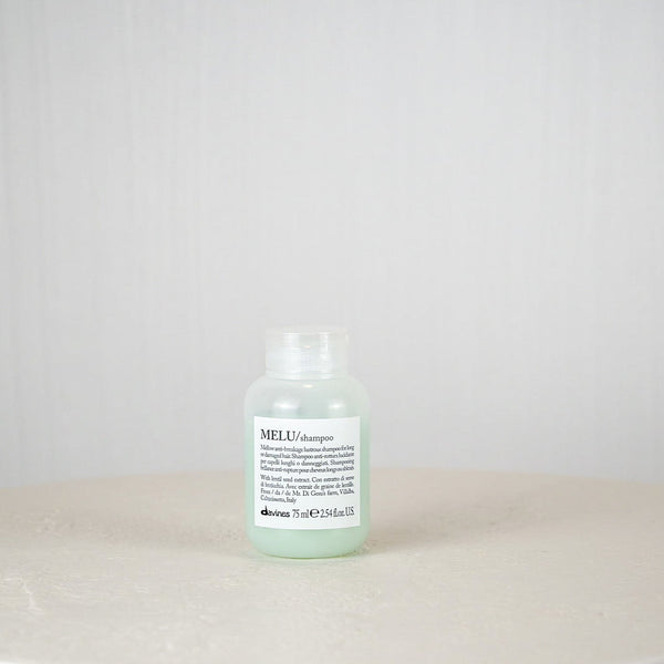 Bottle of MELT shampoo on a white surface with a white background