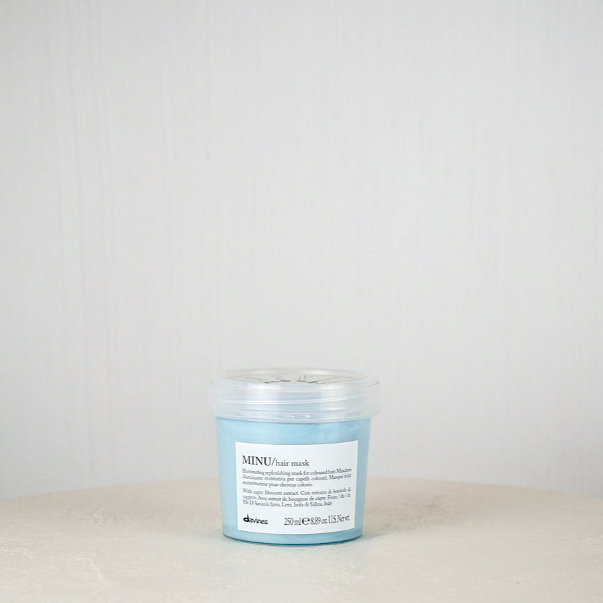Blue jar of Davines hair mask on a white surface with a light gray background