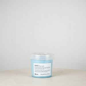 Blue jar of Davines hair mask on a white surface with a light gray background