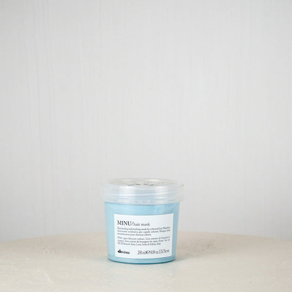 Blue jar of Davines hair mask on a white surface with a light gray background
