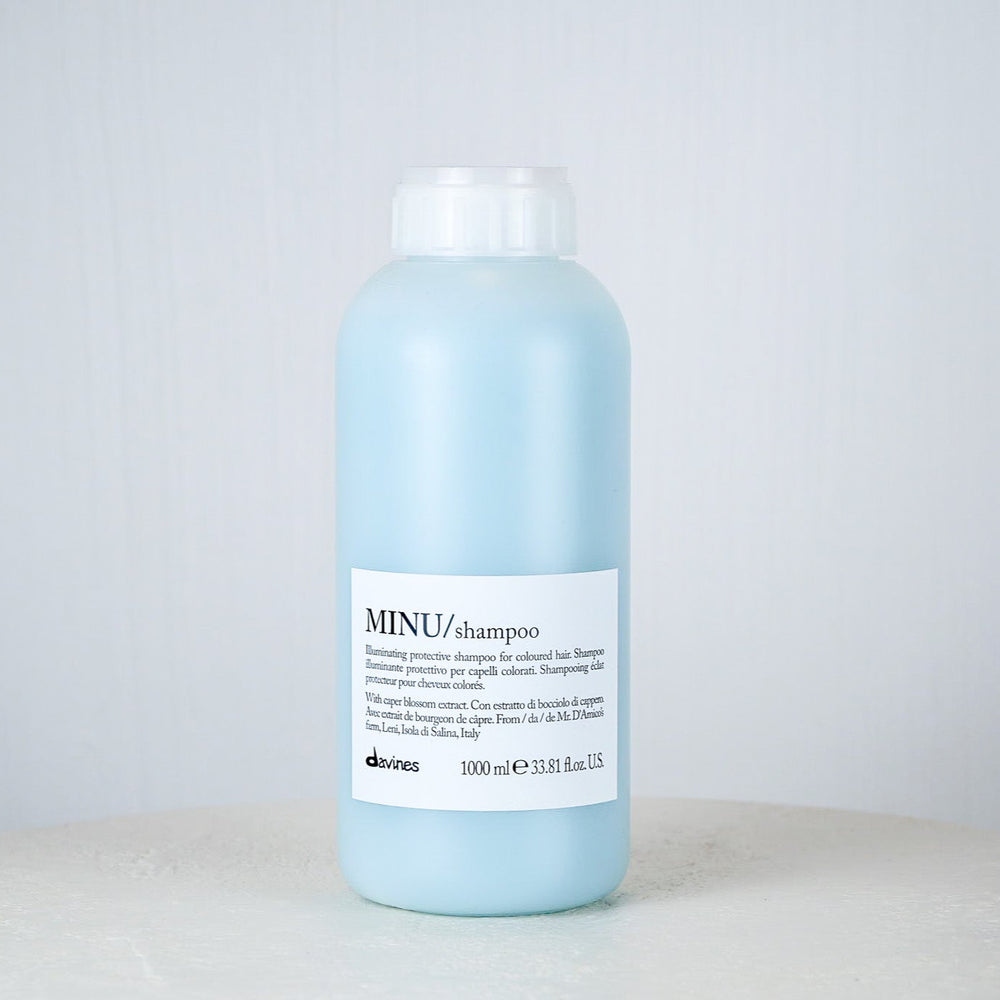 Bottle of Davines MINU shampoo on a light gray background