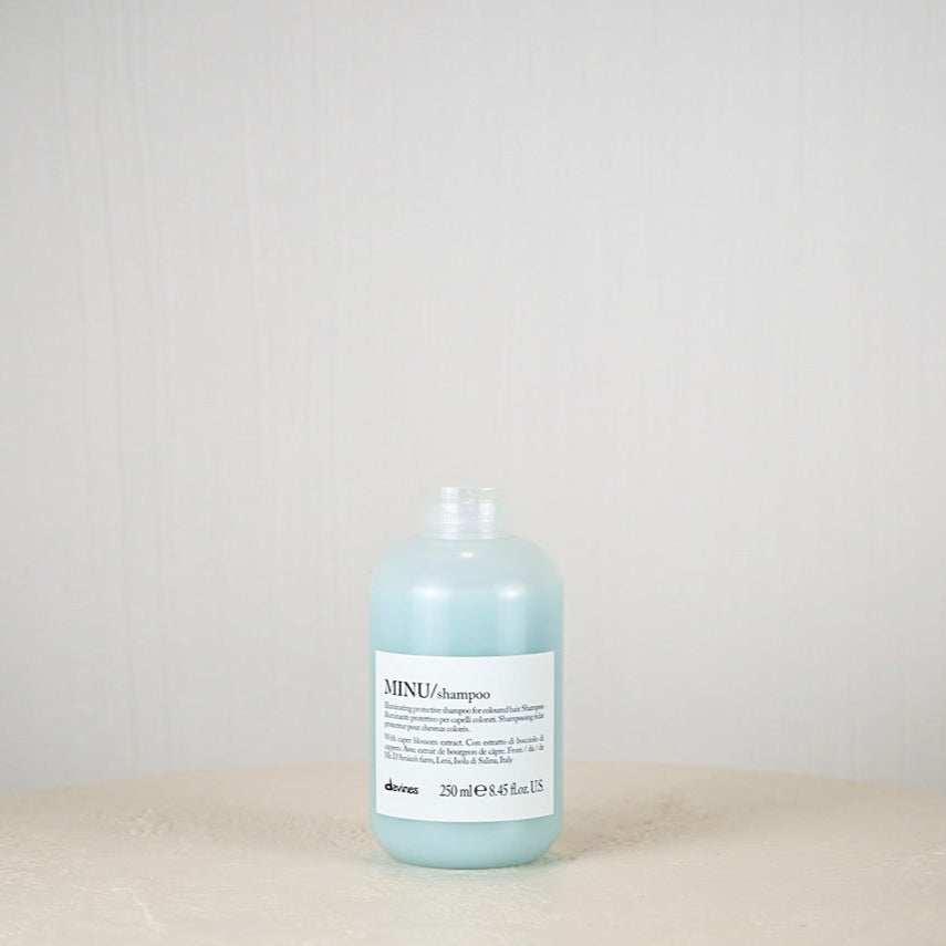 Bottle of Davines MINU shampoo on a light gray background