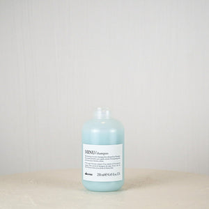Bottle of Davines MINU shampoo on a light gray background