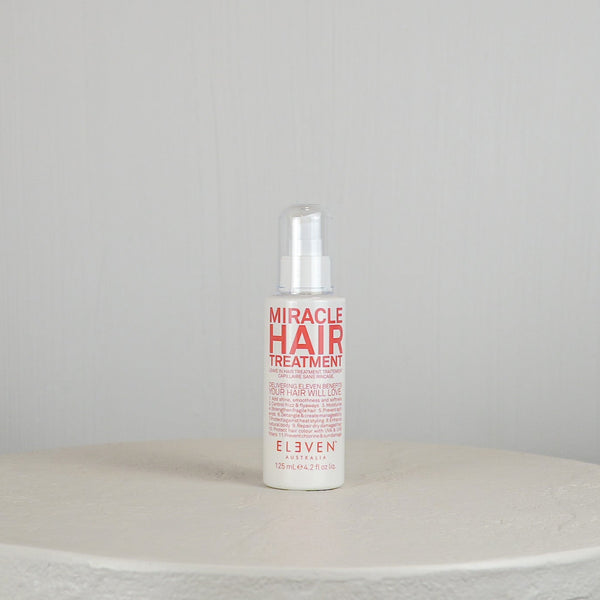 Bottle of 'Miracle Hair Treatment' by Eleven on a white surface with a light gray background