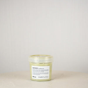 Jar of Momo Conditioner on a beige surface with a light gray background
