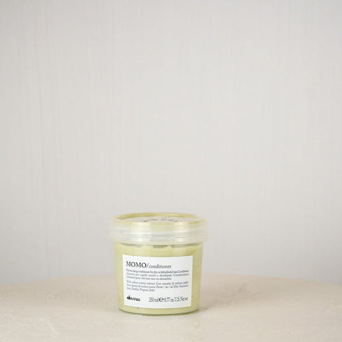Jar of Momo Conditioner on a beige surface with a light gray background