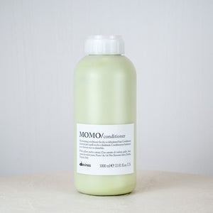 Bottle of MOMO conditioner on a white surface with a light gray background