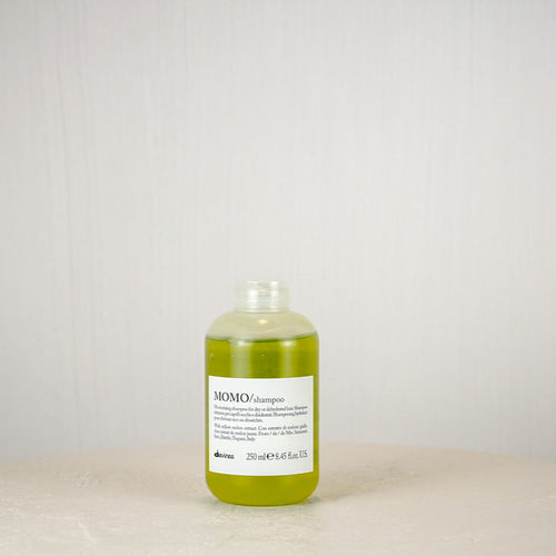 Bottle of shampoo on a white surface with a light gray background