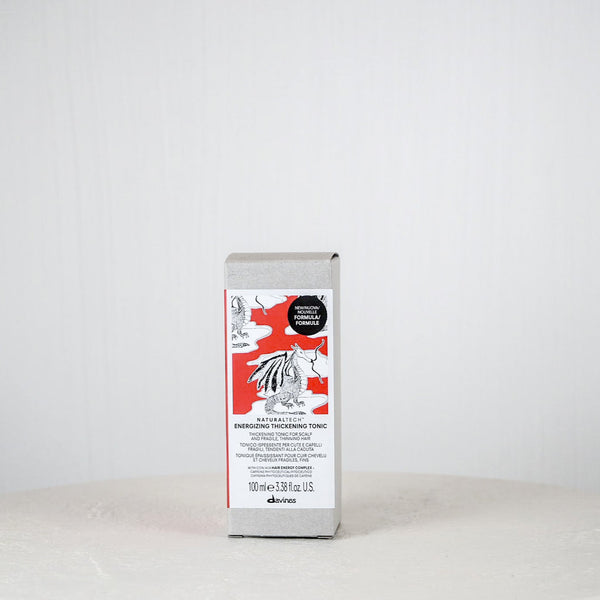 Silver package with a red label on a white surface against a light gray background