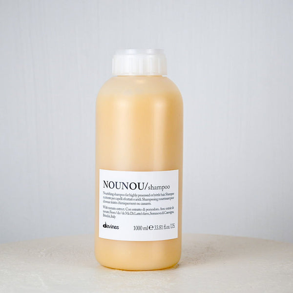 Bottle of NOUNOU shampoo on a white surface with a gray background