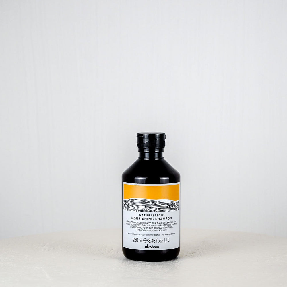 Bottle of Davines shampoo on a white surface with a white background