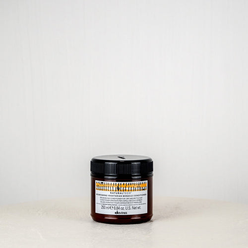 Jar of Davines hair product on a white surface with a white background