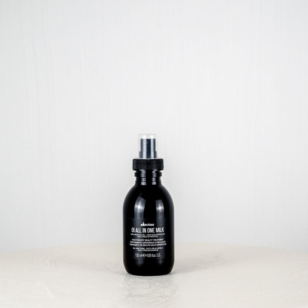 Black bottle of Davines hair product on a white background