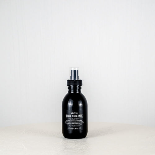Black bottle of Davines hair product on a white background
