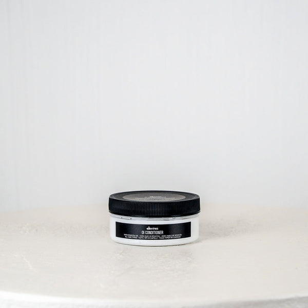 Jar of hair product on a white surface with a light gray background