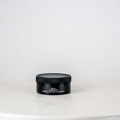 Black cylindrical container on a white surface with a white background