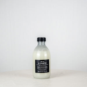 Bottle of Davines shampoo on a white surface with a white background