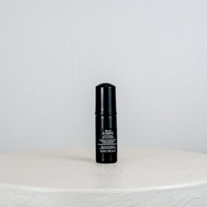 Black bottle with white label on a light gray background