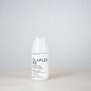 Olaplex bottle on a white surface with a gray background