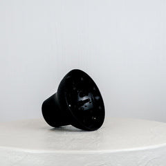 Black plastic component on a white surface with a light gray background