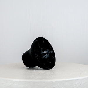 Black plastic component on a white surface with a light gray background