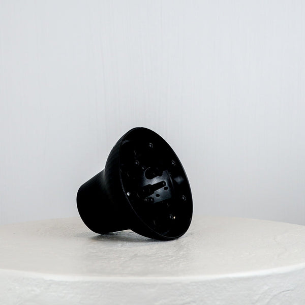 Black plastic component on a white surface with a light gray background