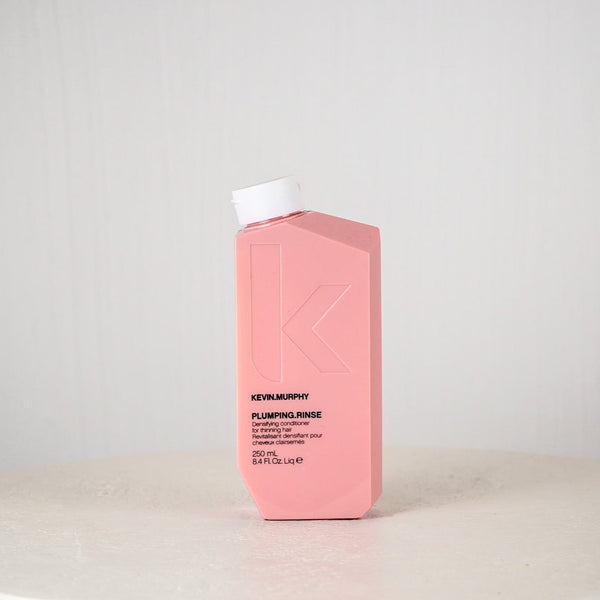 Pink bottle of Kevin Murphy Plumping Rinse on a light gray background