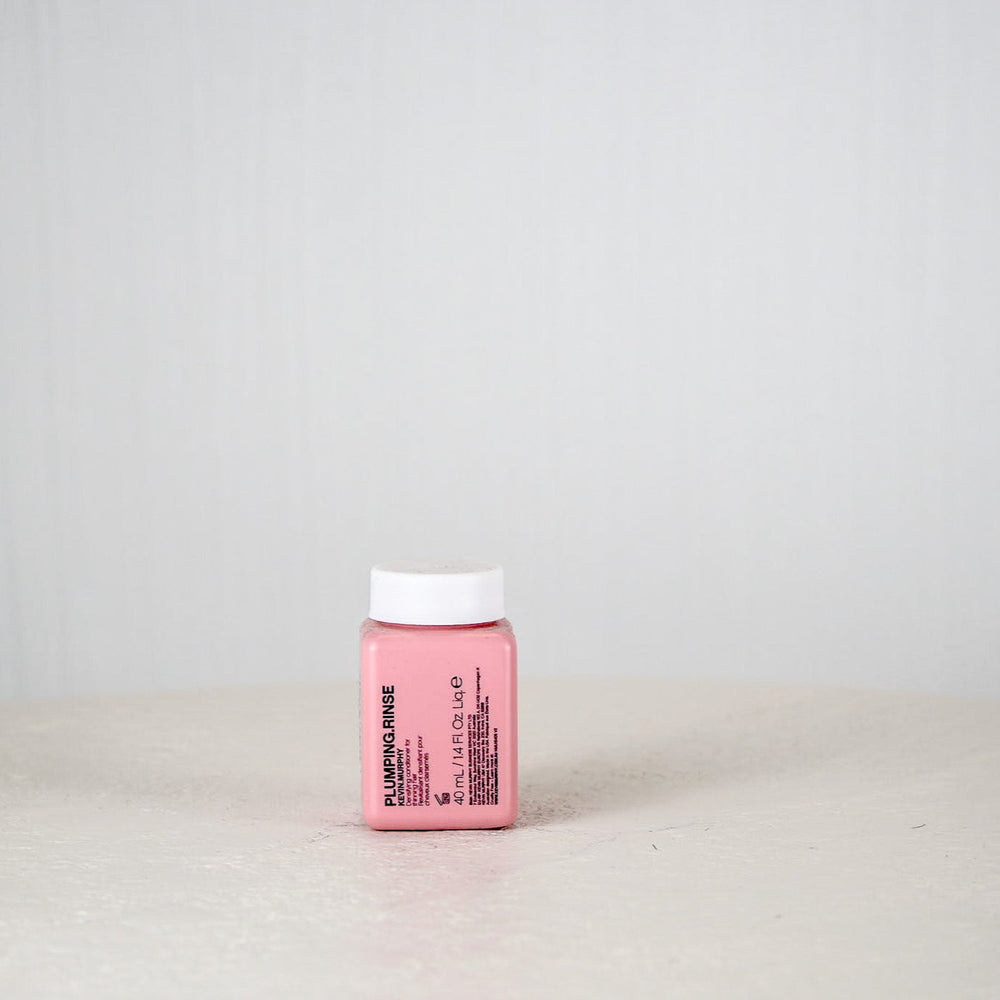 Pink bottle of Kevin Murphy Plumping Rinse on a light gray background
