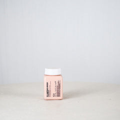 Small pink container with a white cap on a light gray background