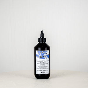 Bottle of Davines hair product on a white surface with a white background
