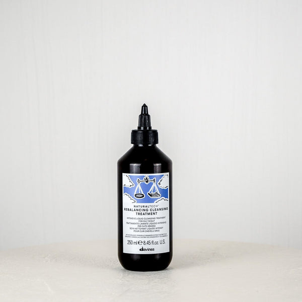Bottle of Davines hair product on a white surface with a white background