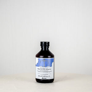 Bottle of Davines Rebalancing Shampoo on a white background