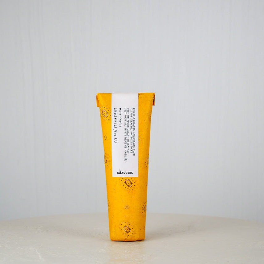 Yellow and white hair product tube with 'davines' branding on a light gray background