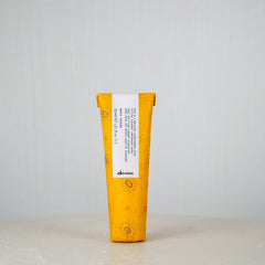Yellow and white hair product tube with 'davines' branding on a light gray background